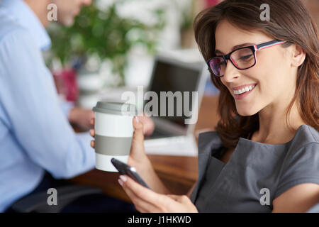 Kaffee trinken und mit Handy Stockfoto