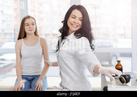 Lächelnde Kosmetikerin mit Dermatoskop zur Untersuchung der Haut bei der Arbeit Stockfoto