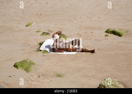 Ein älterer Mann, Sonnenbaden am Strand von Cascais, Lissabon, Portugal. Stockfoto