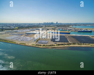 Аerial Ansicht des Yarra River und große importierte Autos Parkplätze in der Nähe von Port Melbourne CBD Skyline in der Ferne. Melbourne, Victoria, Australien Stockfoto