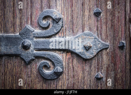 Nahaufnahme von einer Blume-de-Luce geformte Scharnier von einer alten Holztür. Stockfoto