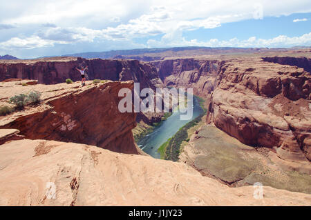 Frau wirft die Arme in Triumph am Horseshoe Bend in Arizona. In der Red Rock Canyon und Green river ermöglichen eine hervorragende Sehenswürdigkeiten. Stockfoto