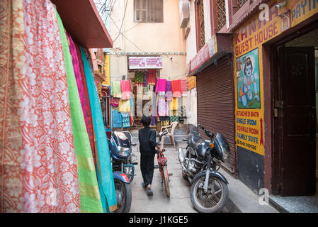 Junge schob sein Fahrrad durch eine schmale Gasse in Varanasi, Indien Stockfoto