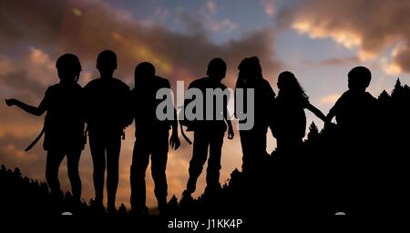 Digital Composite Silhouette Kinder mit Rucksäcken während des Sonnenuntergangs Stockfoto