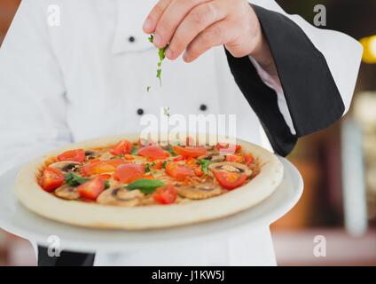 Digitalen Verbund von Koch mit der Pizza in Foregroun im Restaurant. Pizza-Lieferservice Stockfoto