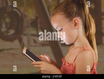 junges Mädchen auf Tablet mit Spielplatz Hintergrund Stockfoto