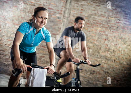 Lächelnde Frau in Sportkleidung auf Fahrrad-Fitness-training Stockfoto