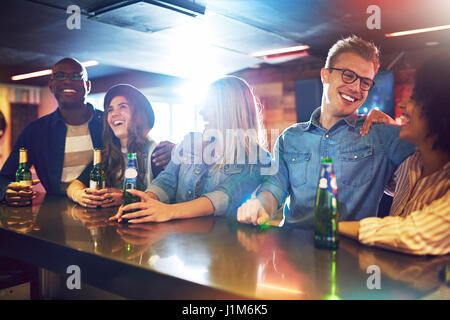 Sitzen an der Bar gegen Freunde lachen und reden miteinander und dabei ein Bier. Stockfoto
