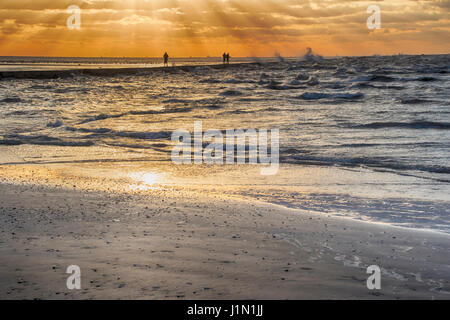 Fischer trotzen Wind und Nässe Sonnenaufgang mit brechenden Wellen auf Galveston East Beach Stockfoto