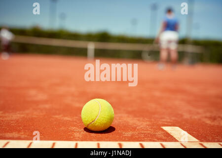 Nahaufnahme eines gelben Tennisball auf rotem Lehm Stockfoto