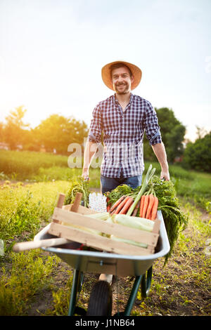 Bauer im Garten mit Gemüse in Schubkarre Stockfoto