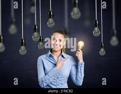 Lächelndes Mädchen hält eine Glühbirne scheint über ihrem Kopf hängen Glühbirnen, die nicht aufleuchten Stockfoto