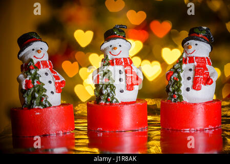 Drei Weihnachten Schneemänner und Herz geformt Lichter im Hintergrund, herzförmige Bokeh Unschärfe, Weihnachtsdekoration Stockfoto