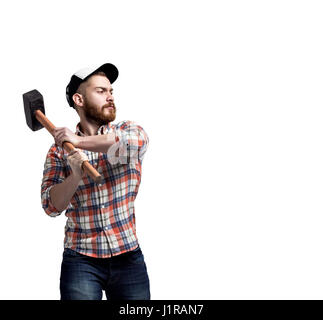 Rothaarige bärtiger Mann trägt eine Baseball-Mütze und Hemd Swunging ein Hammer mit einem Ausdruck. Stockfoto