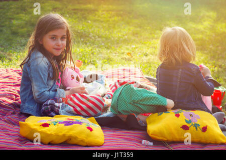 Zwei kleine Mädchen mit Picknick im Garten Stockfoto