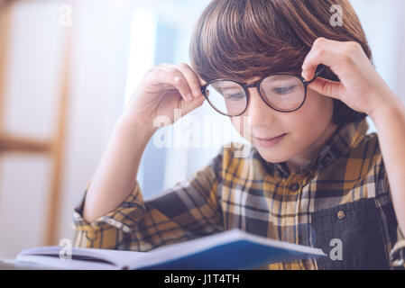 Intelligente neugieriger Junge immer näher betrachten Sie Notizen Stockfoto