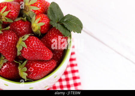 Rip frische Erdbeeren in einer Schüssel auf weißer Holztisch Stockfoto