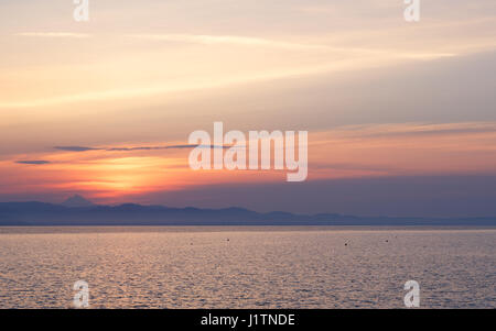 Am frühen Morgen bei Sonnenaufgang des Tages mit einem ruhigen blauen Meer mit Blick auf den Himmel und die Berge des anderen Ufers, Kassandra, Griechenland Stockfoto