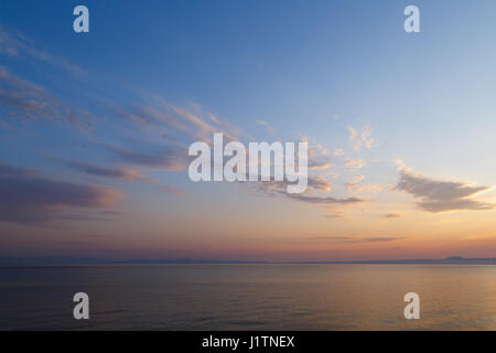 Am frühen Morgen bei Sonnenaufgang des Tages mit einem ruhigen blauen Meer mit Blick auf den Himmel und die Berge des anderen Ufers, Kassandra, Griechenland Stockfoto