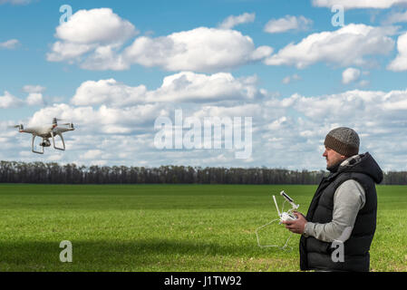 man Betrieb von fliegenden Drohne Quadrocopter auf der grünen Wiese. Stockfoto