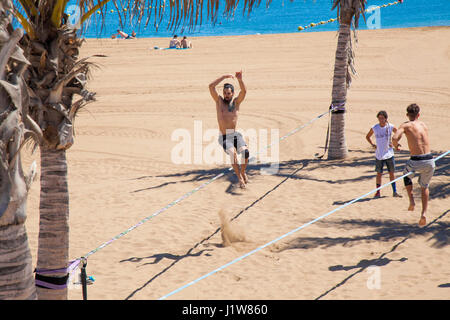 LAS PALMAS - 15 April: Eine Gruppe Pf junge Männer üben Slacklinen am Strand von Playa de Las Alcaravaneras, 15. April 2016 in Las Palmas, Gran Canaria, Sp Stockfoto