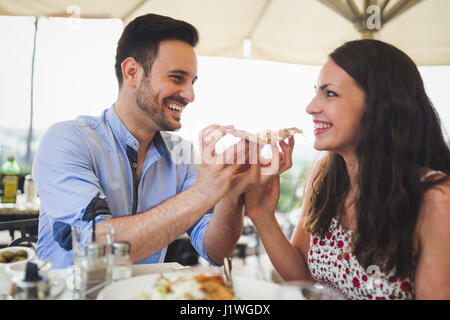 Romantisch zu zweit teilen ein Stück Pizza im freien Stockfoto