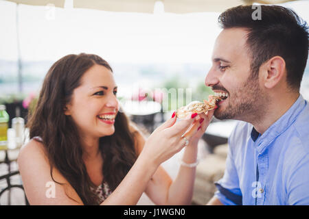 Romantisch zu zweit teilen ein Stück Pizza im freien Stockfoto