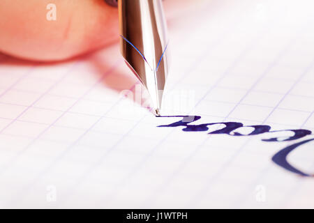 Nahaufnahme Bild Füllfederhalter mit blauer Tinte schreiben auf quadratischen notebook Stockfoto