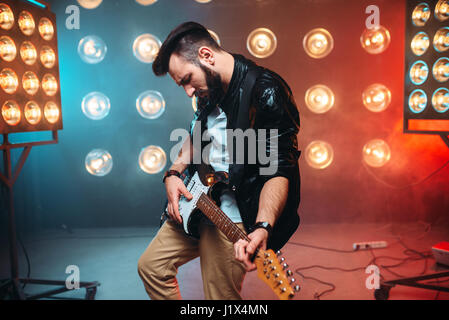 Männliche Solo-Musiker mit Elektro-Gitarre auf der Bühne mit den Dekorationen der Lichter. Musikalische Unterhaltung. Stockfoto