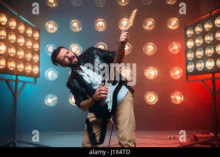 Männliche Solo-Musiker mit Elektro-Gitarre auf der Bühne mit den Dekorationen der Lichter. Musikalische Unterhaltung. Stockfoto