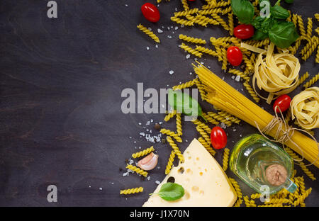 Zutaten für das Kochen italienischen Pasta - Spaghetti, Fusilli, Bandnudeln, Basilikum, Kirschtomaten, Knoblauch, Pfeffer und Käse. Draufsicht mit Platz für Text. Stockfoto