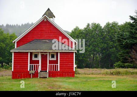 Kleine rote Schulhaus in Wiese am nebligen Morgen Stockfoto