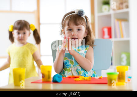 Niedliche kleine Mädchen Formen aus Plastilin auf Tisch Stockfoto