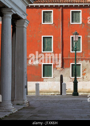 Altbauwohnung in Venedig mit verblassten roten Wand und grünen Fensterläden Stockfoto