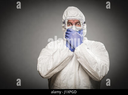 Manndeckung Mund mit Händen HAZMAT Schutzkleidung vor einem grauen Hintergrund. Stockfoto