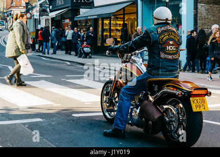 Mann auf einer Harley Davidson Motorrad mit passenden Logo Denim Jacke warten auf Fußgängerüberweg eine Straße in Hampstead, London. Stockfoto