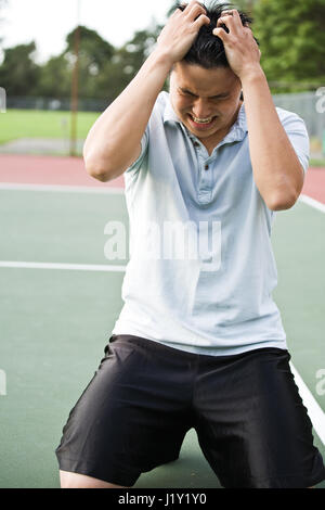 Ein asiatischer Tennisspieler enttäuscht in der Niederlage nach einem Tennismatch Stockfoto