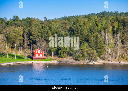 Schwedische ländliche Landschaft, Dorf an der Küste mit roten Holzhaus Stockfoto