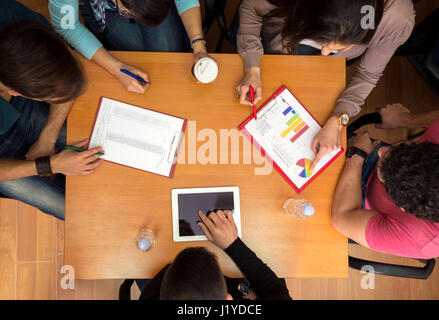 Draufsicht der Arbeitstisch mit Studenten, Tablet und Statistiken in der Teamarbeit Stockfoto