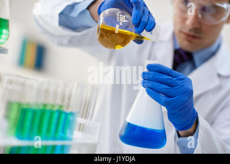 Männliche Forscher untersuchen Flaschen mit verschiedenen Proben im Labor Stockfoto