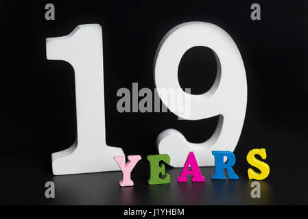 Buchstaben und Zahlen neunzehn Jahre auf schwarzem Hintergrund isoliert. Stockfoto