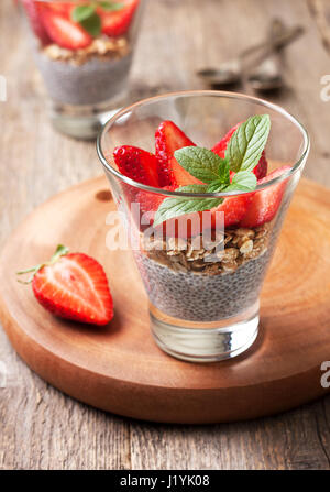 Ernährung, gesundes Frühstück. Chia Pudding, Erdbeeren und Müsli in einem Glas frischen Erdbeere auf alten hölzernen Hintergrund Stockfoto