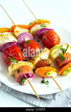 Gegrillte Wurst und Gemüse-Spieße mit frischen Kräutern auf weißen Teller Stockfoto