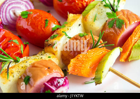 Gegrillte Wurst und Gemüse-Spieße mit frischen Kräutern auf weißen Teller Stockfoto