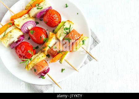 Gegrillte Wurst und Gemüse-Spieße mit frischen Kräutern auf weißen Teller Stockfoto