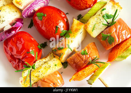 Gegrillte Wurst und Gemüse-Spieße mit frischen Kräutern auf weißen Teller Stockfoto