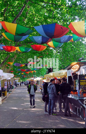 Padua, Italien, 22. April 2017. Eine bunte Reihe von Ständen verkaufen Suppen und Getränke für den Sommer Movida öffnet. Wie in den vergangenen Jahren verbringen eine Menge junge Leute ihre Nächte auf der Razzle in der schönen Allee von Linden, die entlang des Kanals Piovego, im universitären Bereich. Einige Hunderte regenbogenfarbige Regenschirme, hängen kopfüber an den Zweigen der Bäume, Girlande die Avenue. -Ferdinando Piezzi Stockfoto