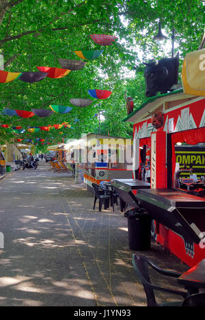 Padua, Italien, 22. April 2017. Eine bunte Reihe von Ständen verkaufen Suppen und Getränke für den Sommer Movida öffnet. Wie in den vergangenen Jahren verbringen eine Menge junge Leute ihre Nächte auf der Razzle in der schönen Allee von Linden, die entlang des Kanals Piovego, im universitären Bereich. Einige Hunderte regenbogenfarbige Regenschirme, hängen kopfüber an den Zweigen der Bäume, Girlande die Avenue. -Ferdinando Piezzi Stockfoto