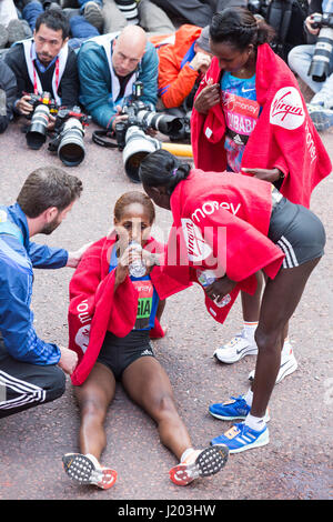 London, UK. 23. April 2017. 3. platzierten Aselefech Mergia (ETH) stürzt nach der Ziellinie und wird vom Sieger geholfen Mary Keitany (KEN) und zweite platziert Tirunesh Dibaba (ETH). 37. London-Marathon endet an der Mall. Bildnachweis: Bettina Strenske/Alamy Live-Nachrichten Stockfoto