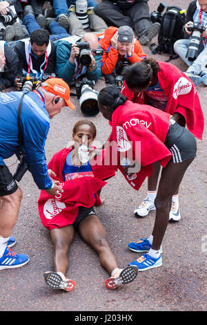 London, UK. 23. April 2017. 3. platzierten Aselefech Mergia (ETH) stürzt nach der Ziellinie und wird vom Sieger geholfen Mary Keitany (KEN) und zweite platziert Tirunesh Dibaba (ETH). 37. London-Marathon endet an der Mall. Bildnachweis: Bettina Strenske/Alamy Live-Nachrichten Stockfoto